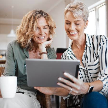 Two ladies smiling at tablet