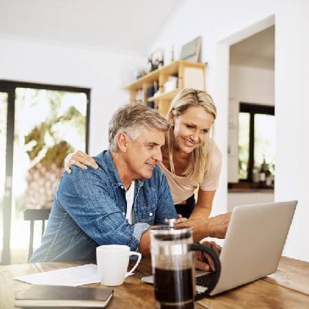 Middle aged couple looking at laptop | Why so many over 55s take pension cash early