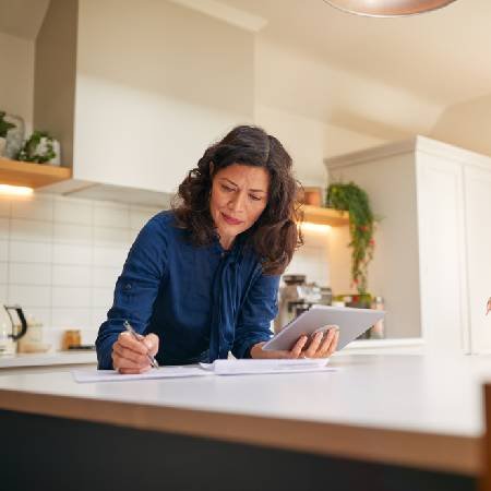 Lady holding tablet whilst reading her pension paperwork