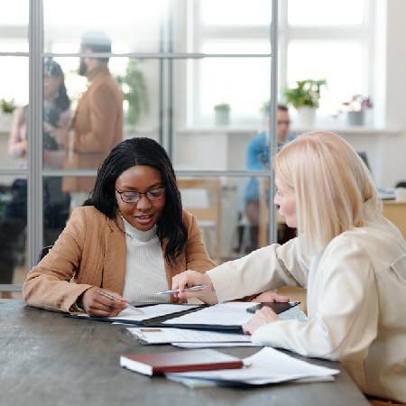 Two women in the workplace discussing opting out of their workplace pension