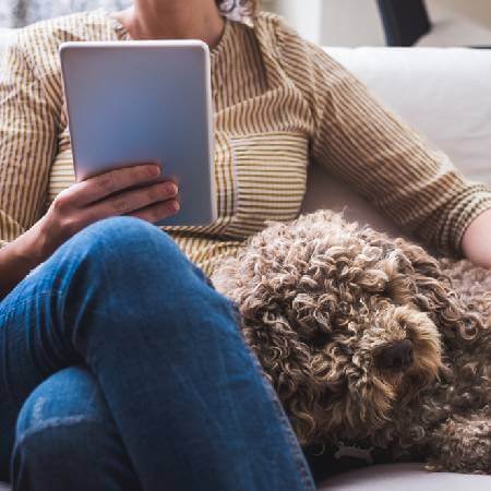 Lady using tablet on the sofa with dog | 5 ways to enhance your pension savings