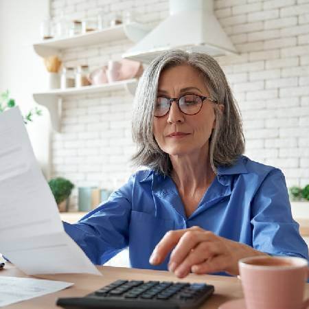 Lady in the kitchen calculating her spending on the food shop