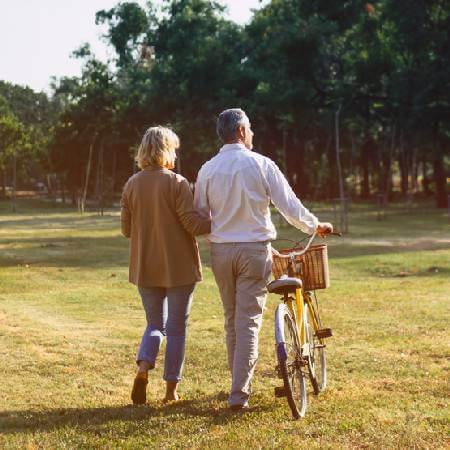 Couple with bike on a walk across a field 