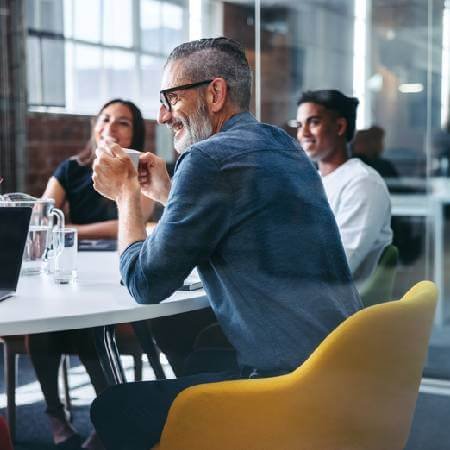 Man smiling in glass office with colleagues | Maximise pension savings