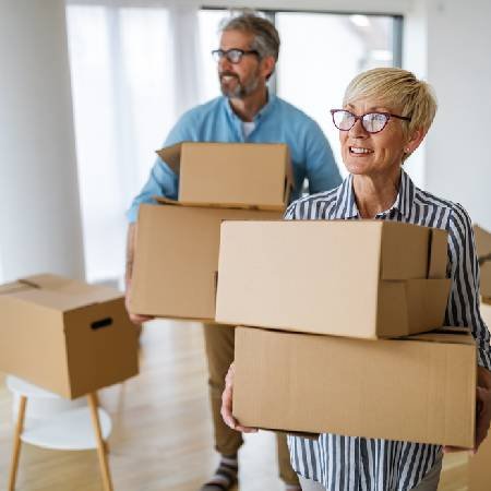 Couple moving house carrying boxes | Downsizing for retirement