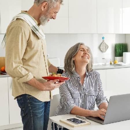 Mature couple laughing in the kitchen | Majority of people aren’t open about money with their partner