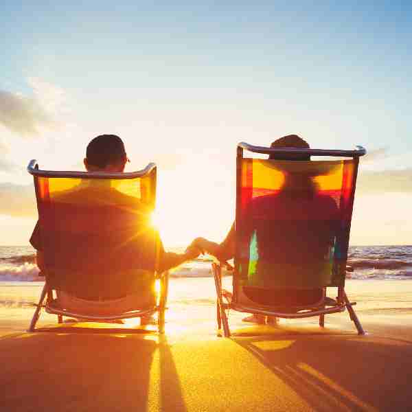 Man and woman sitting on deckchairs holding hands