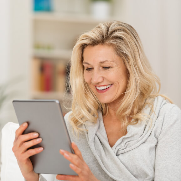 Two ladies smiling at tablet